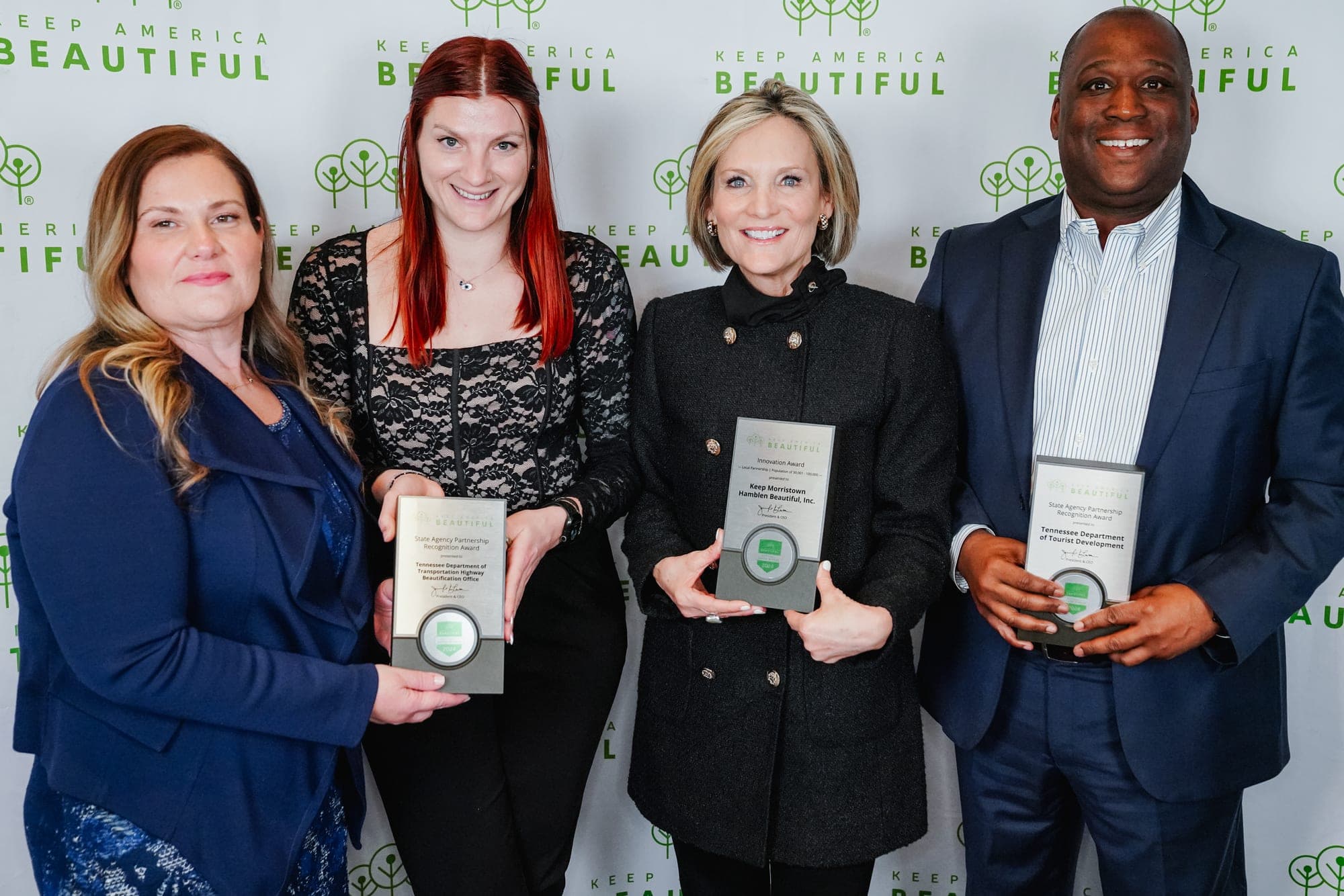 Four people stand in front of a Keep America Beautiful step-and-repeat backdrop, three of them holding award plaques, at the 2025 national conference.