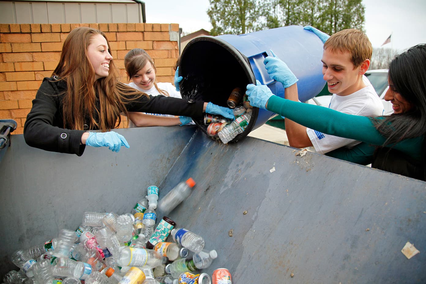 A curbside recycling bin filled with flattened cardboard and rinsed containers, ready for collection.