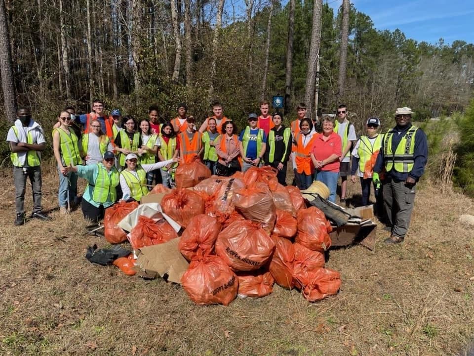 A Keep Berkeley Beautiful group gathered on a cleared street corner after a cleanup, holding collection bags and grabbers together for a group photograph.